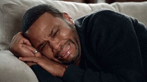 Man lying on a couch crying with his face scrunched up