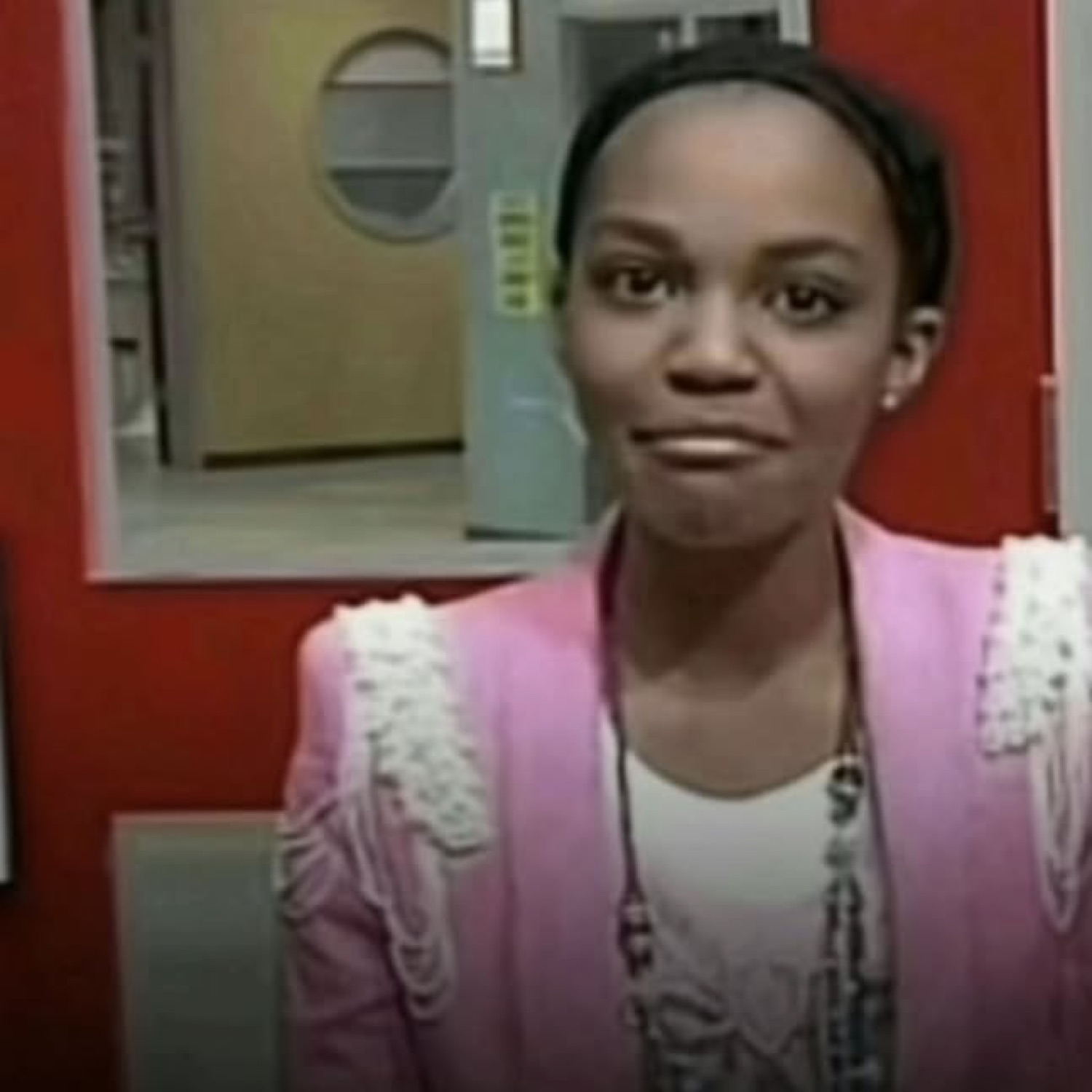 Woman in a pink blazer pressing her lips tight in a strained, polite non-smile