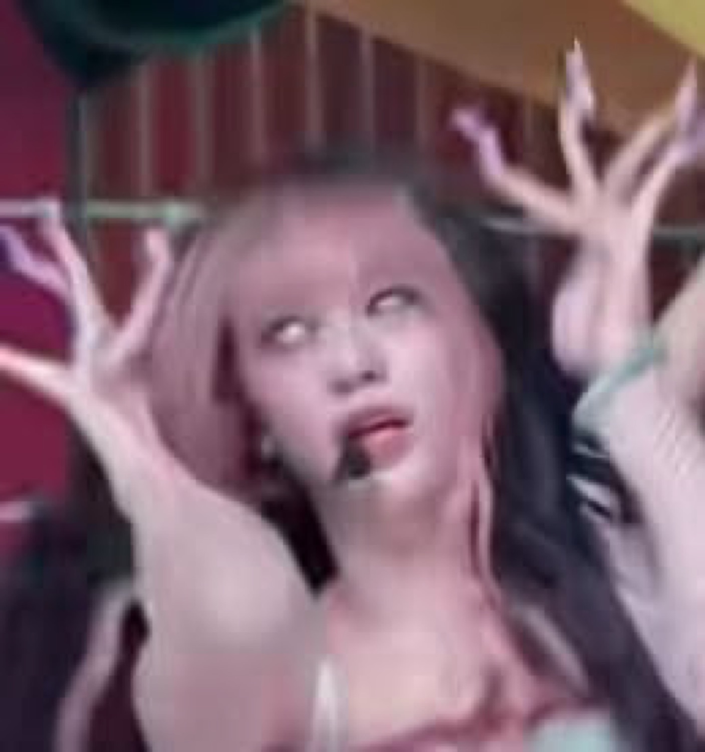 Blurry stage shot of a performer with eyes rolled back and both hands clawing the air
