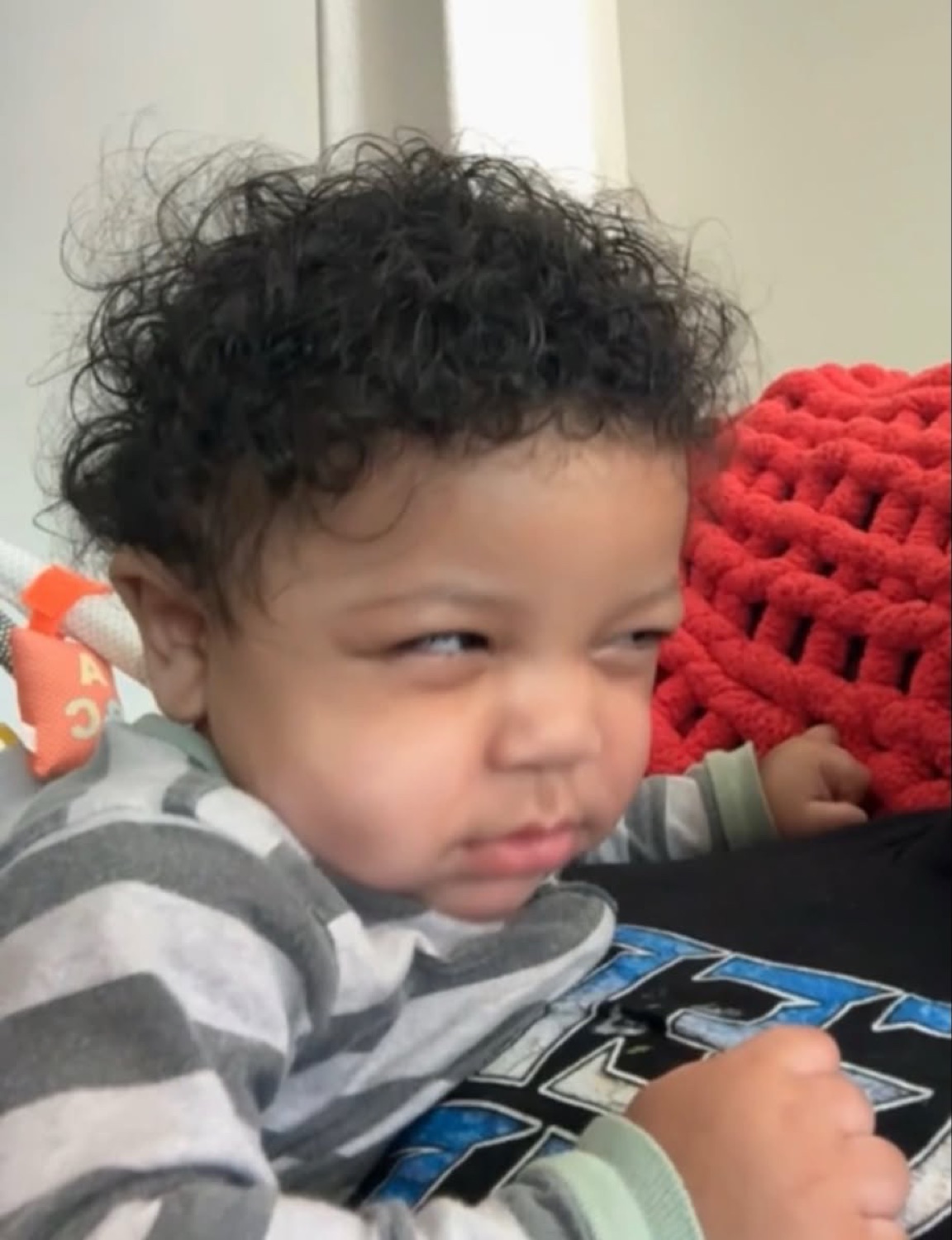 Curly-haired baby giving a scrunched, deeply skeptical side-glance