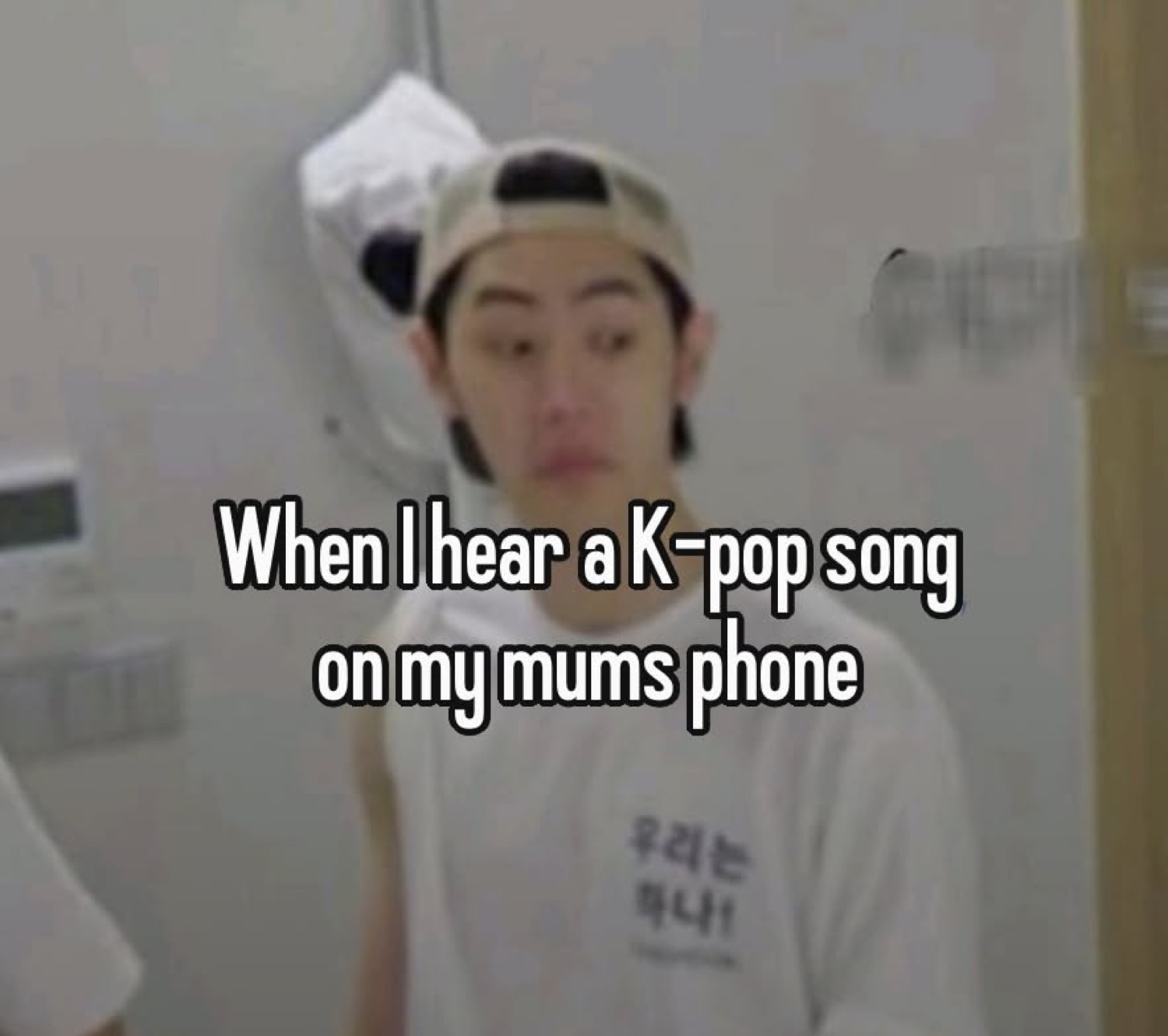 Guy in a backwards cap frozen mid-stare with text 'When I hear a K-pop song on my mums phone'