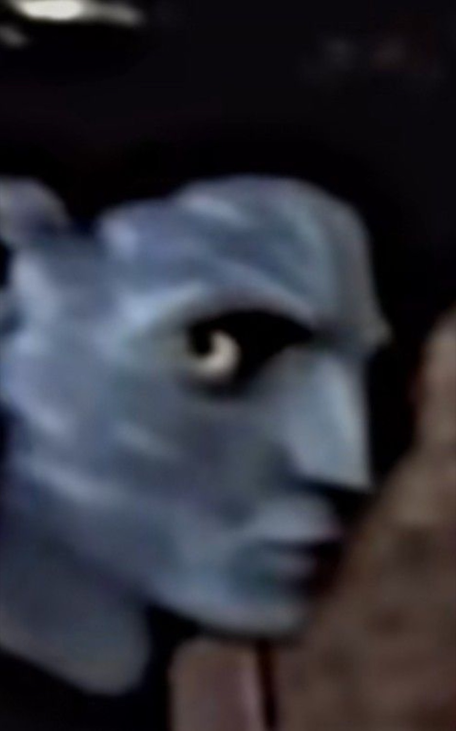 Blurry blue Na'vi-looking face peering sideways out of the dark