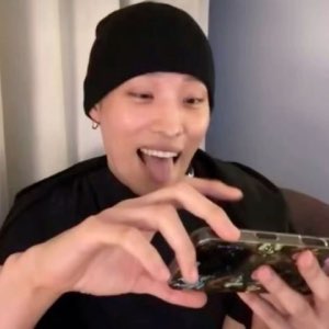 Guy in a beanie sticking his tongue out, eagerly holding a phone up to his mouth