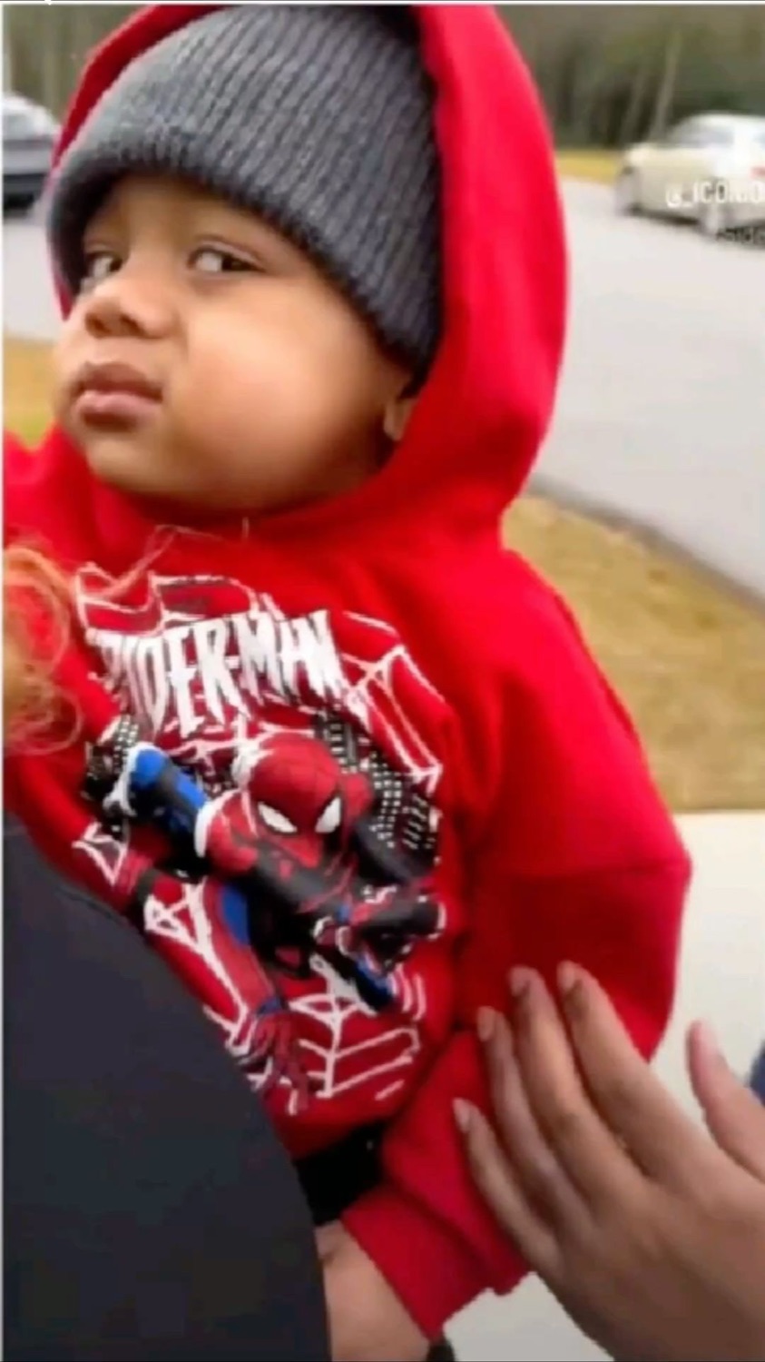 Toddler in a Spider-Man hoodie and beanie shooting a flat, unimpressed side glance
