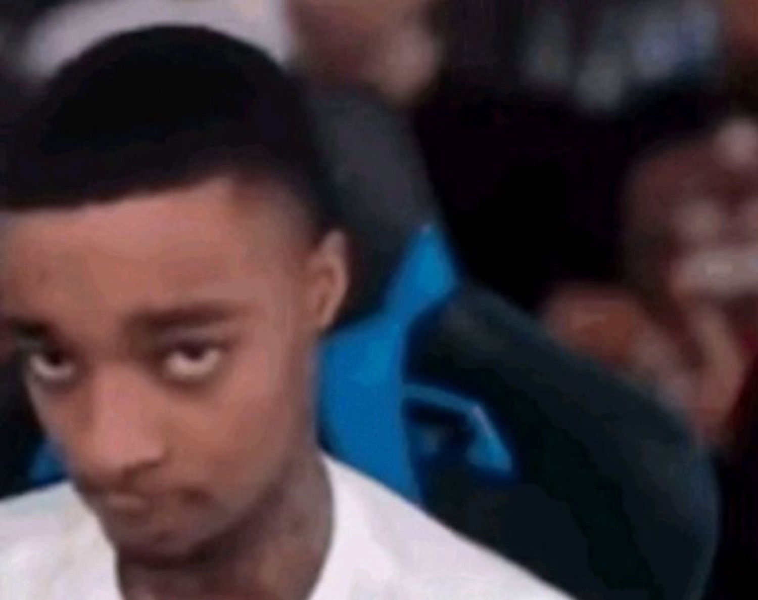 Young man glancing sideways with a deeply skeptical side-eye in a crowded venue