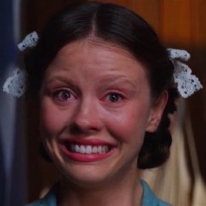 Young woman in pigtails forcing a shaky smile through teary, red-rimmed eyes