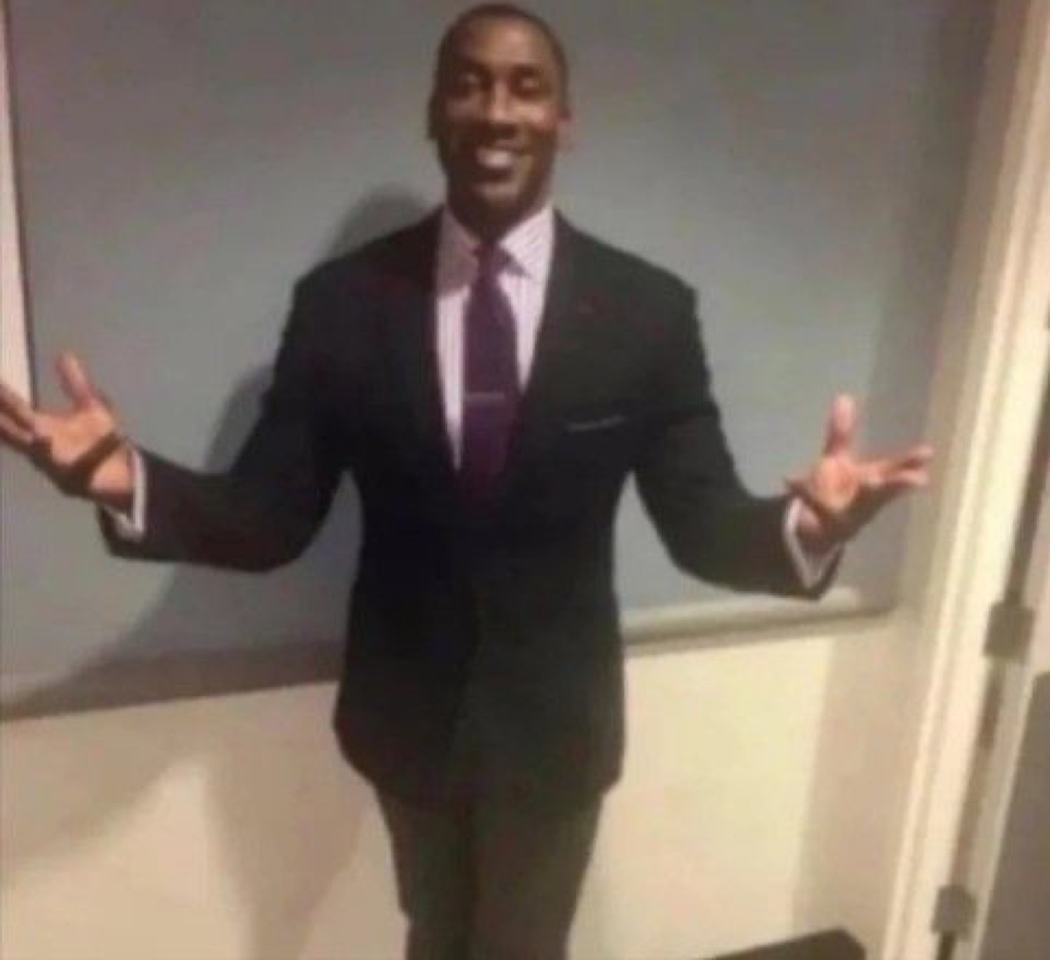 Man in a suit standing with his arms open in a welcoming gesture