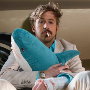 Man with a cigarette and bandaged hand clutching a plush shark, totally deadpan