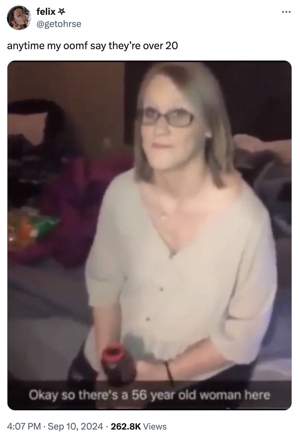 Tweet of the 'Okay so there's a 56 year old woman here' FaceApp screenshot: a woman in glasses and a cream cardigan staring blankly at the camera