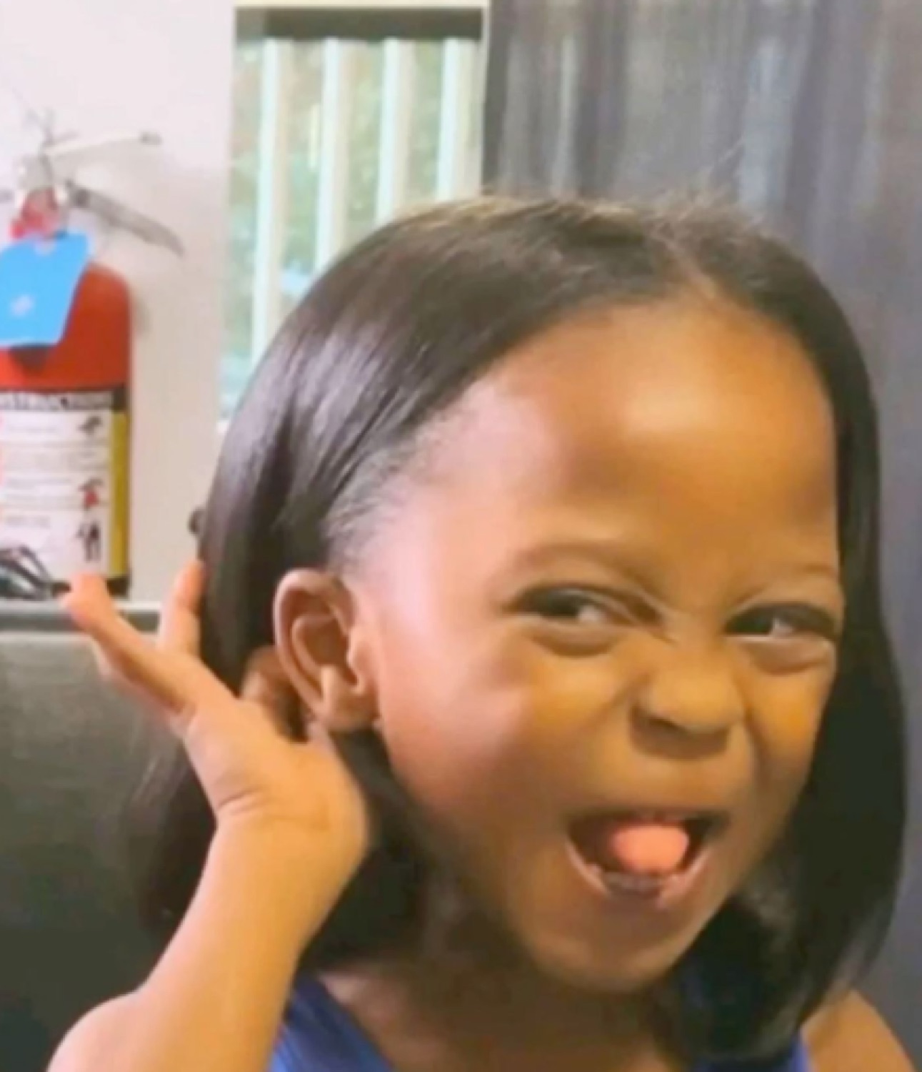 Little girl cupping her ear with her tongue out: 'what?'
