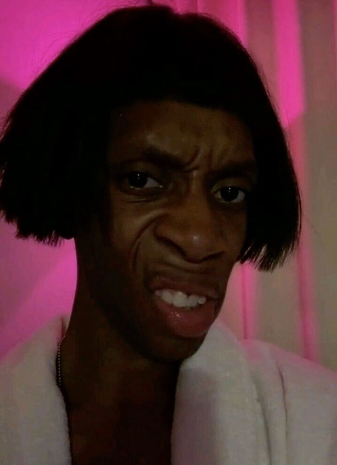 Man in a bob wig with a sour, disgusted grimace
