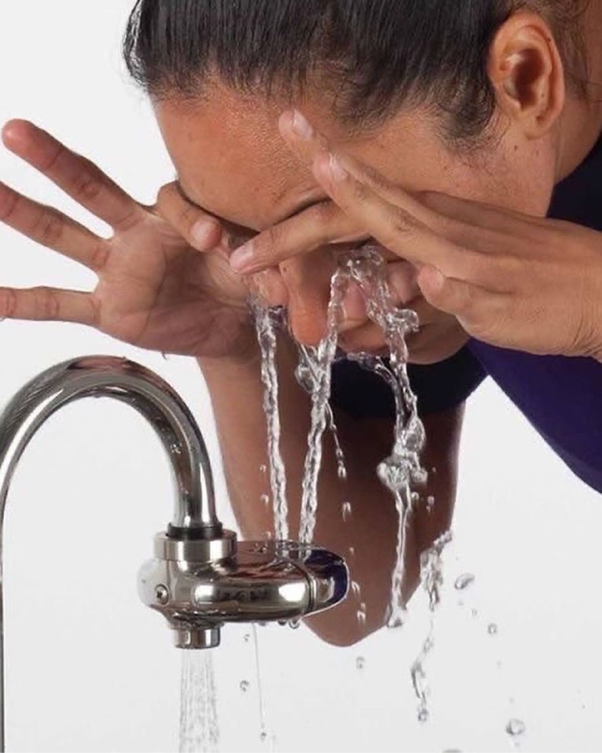 Person splashing water on their face at the sink as if washing away the day