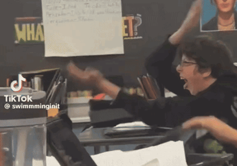 Kid in a classroom flailing his arms back and forth doing the six seven meme