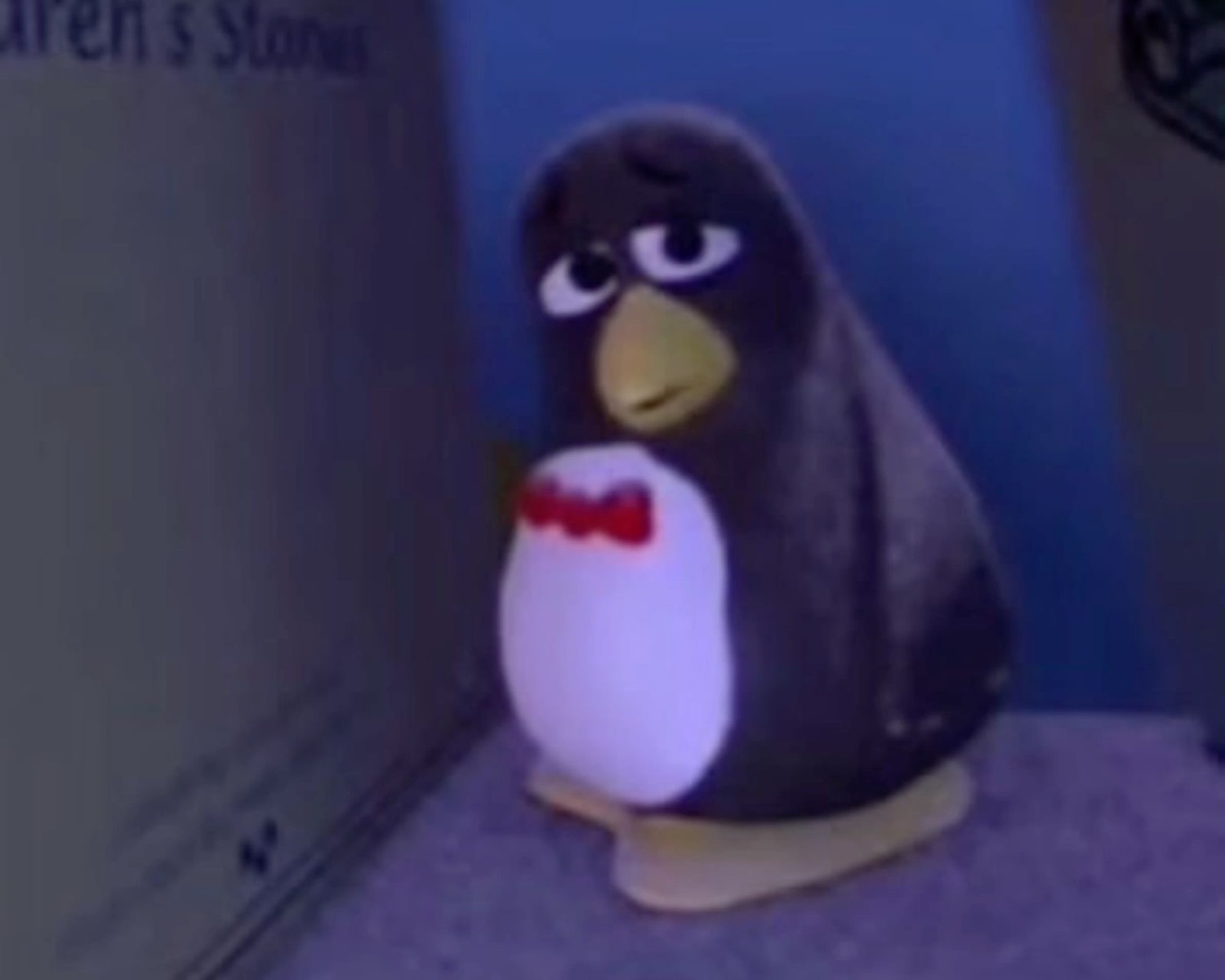 Grumpy-faced penguin figurine in a bow tie staring down the camera with pure contempt