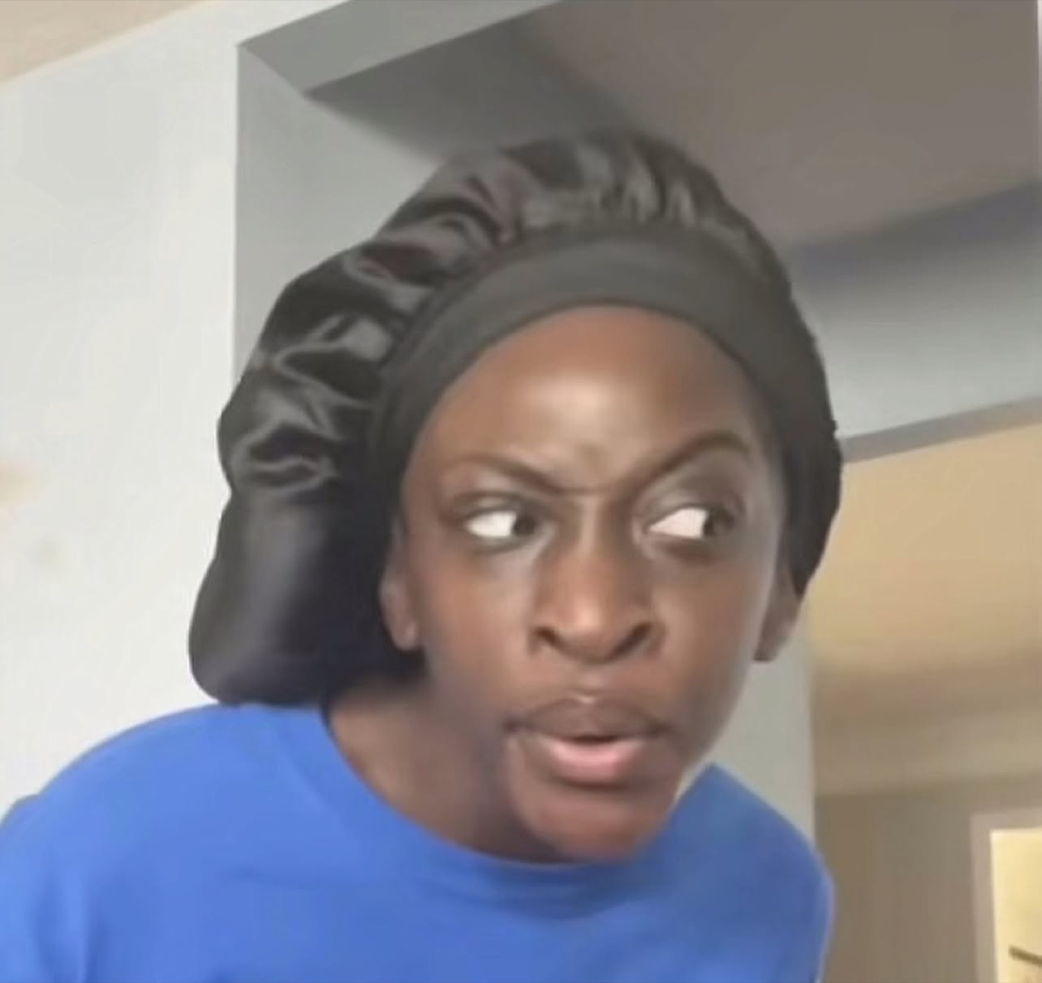Woman in a satin bonnet throwing a hard side-eye with her mouth slightly open