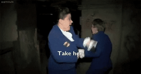 Two men in blue suits struggling in a dark room, "Take her!"