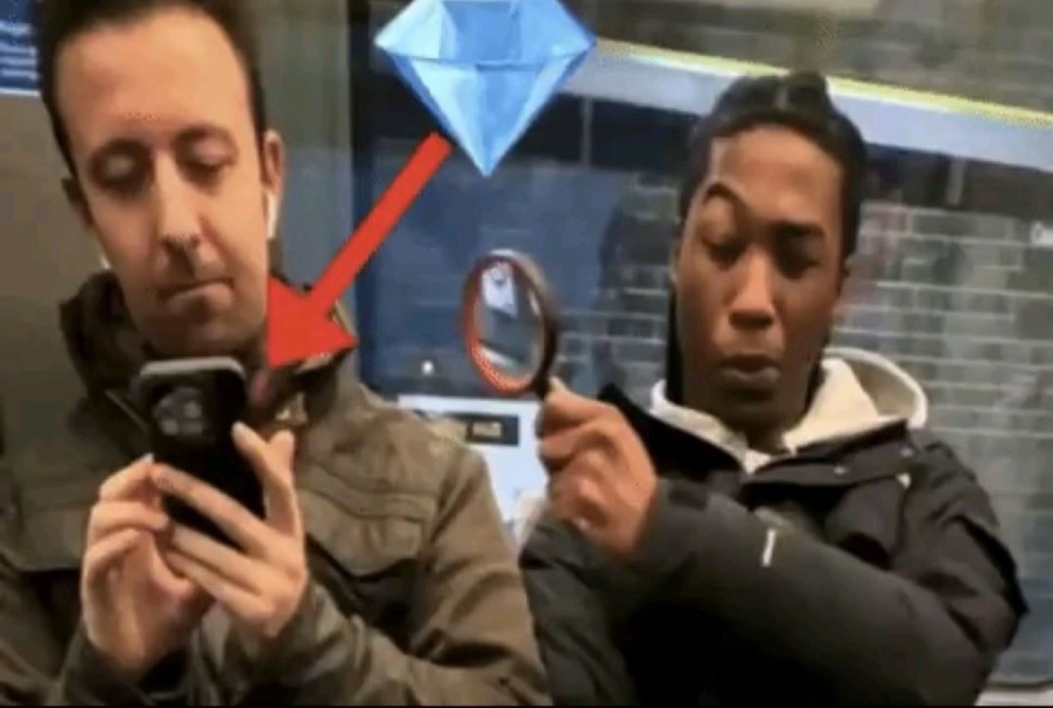 Two guys on a train, a diamond and red arrow pointing at one staring hard at the other's phone
