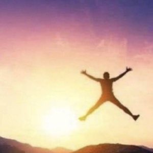 Silhouette jumping in a star shape against a glowing sunset