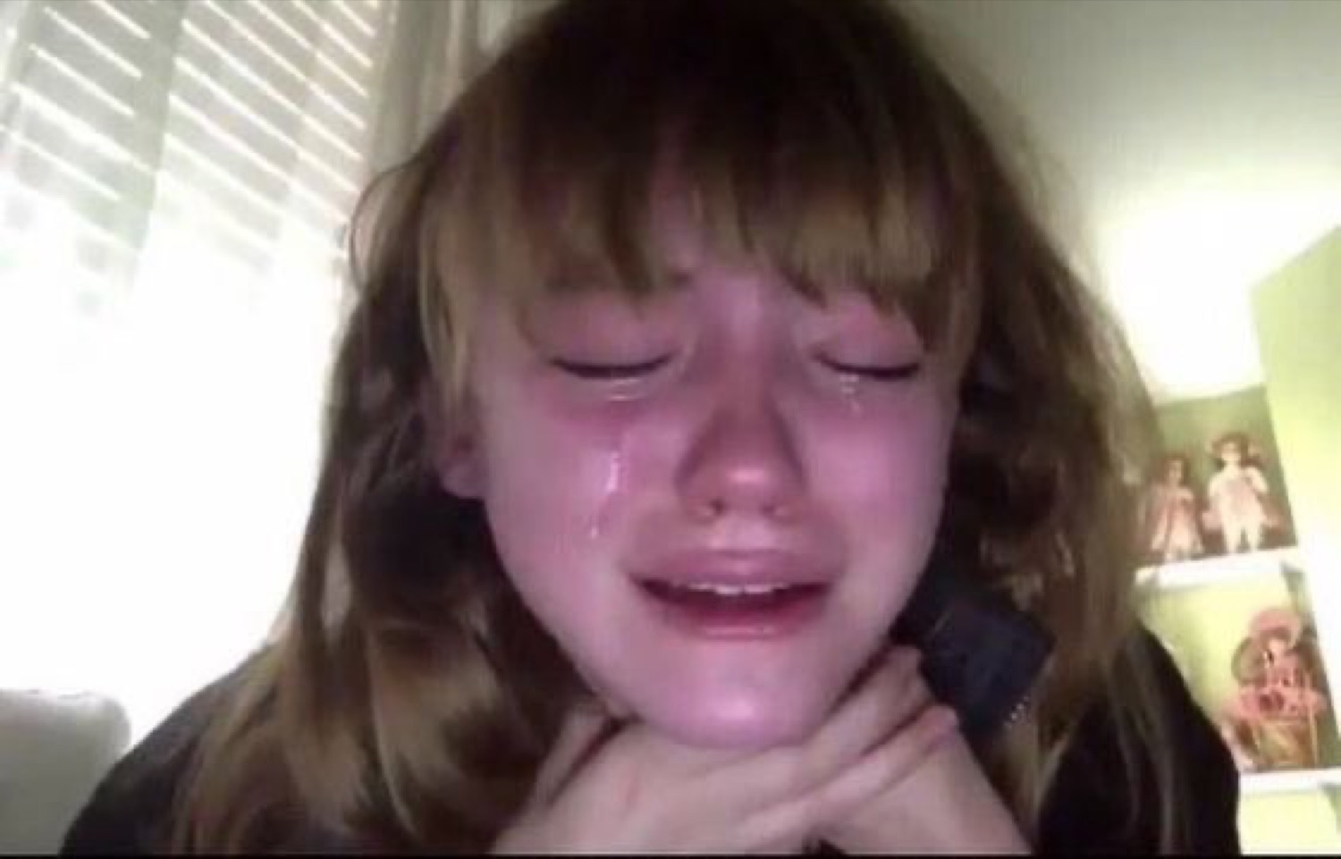 Young girl sobbing with tears streaming down her face on webcam