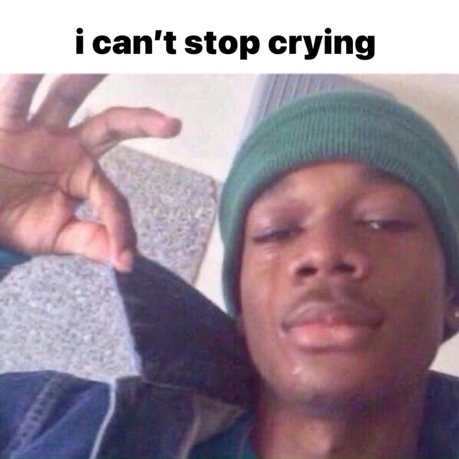 Teary-eyed guy in a beanie throwing an OK sign captioned 'i can't stop crying'