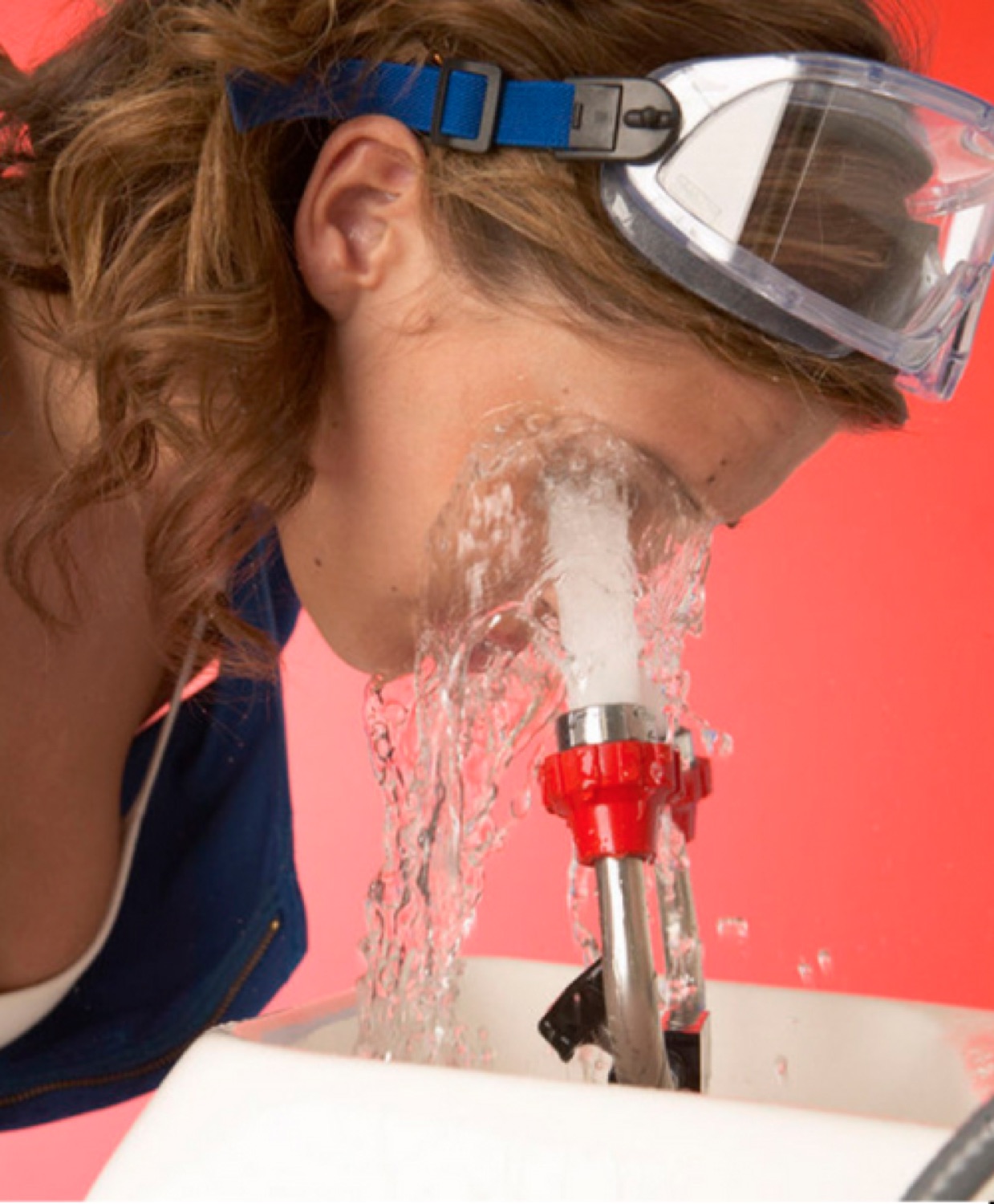 Woman in safety goggles getting blasted in the face by an eyewash station