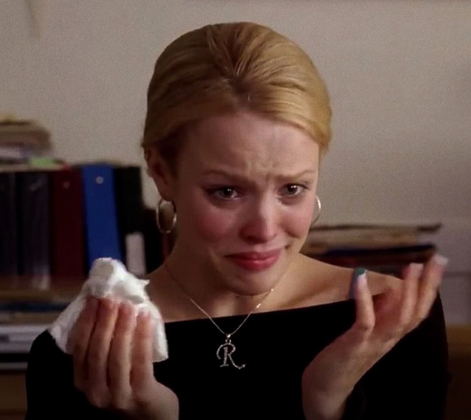 Blonde woman in black dress sobbing with a tissue and painted nails, utterly falling apart
