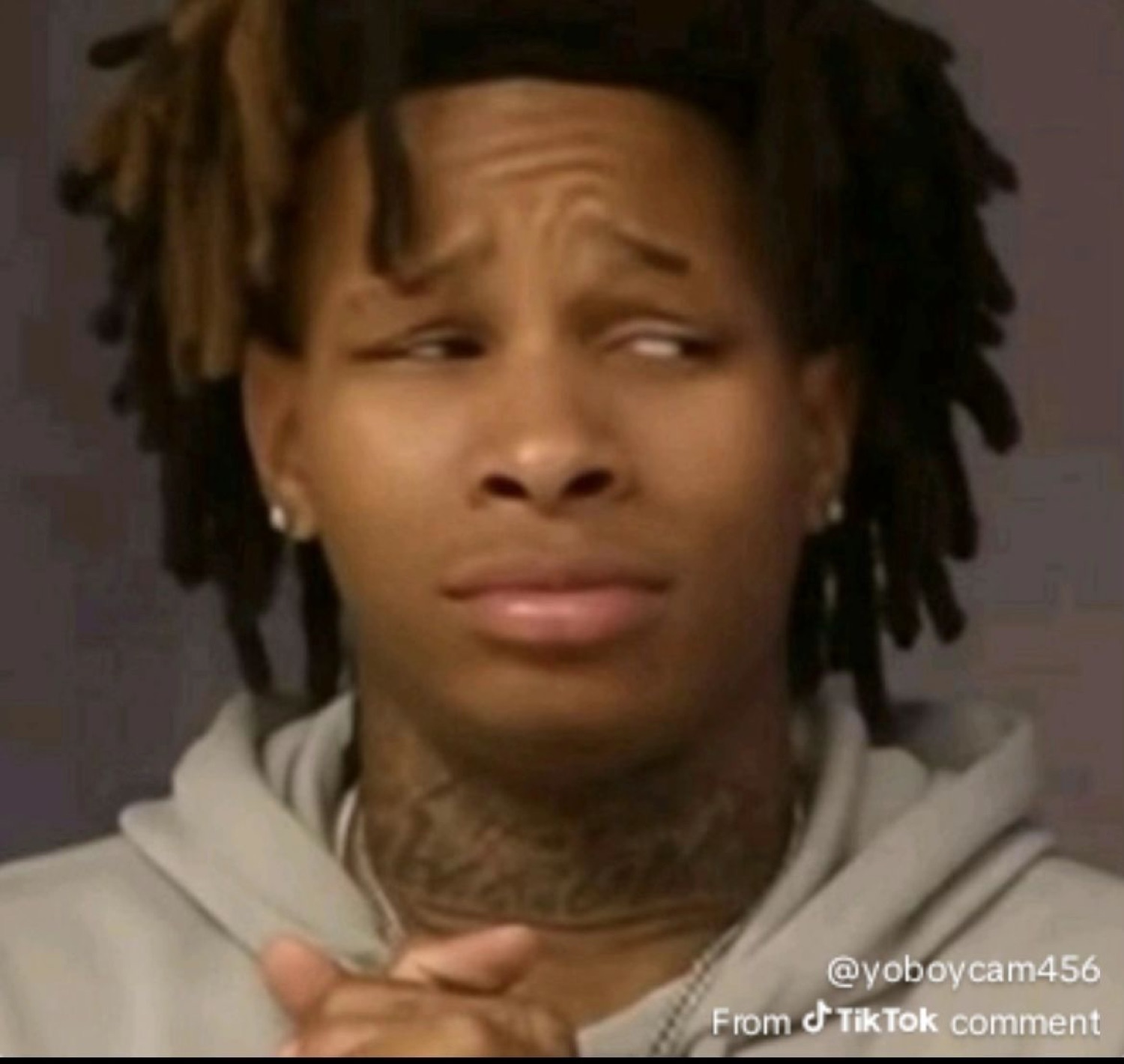 Man with dreads making an awkward, unconvinced face