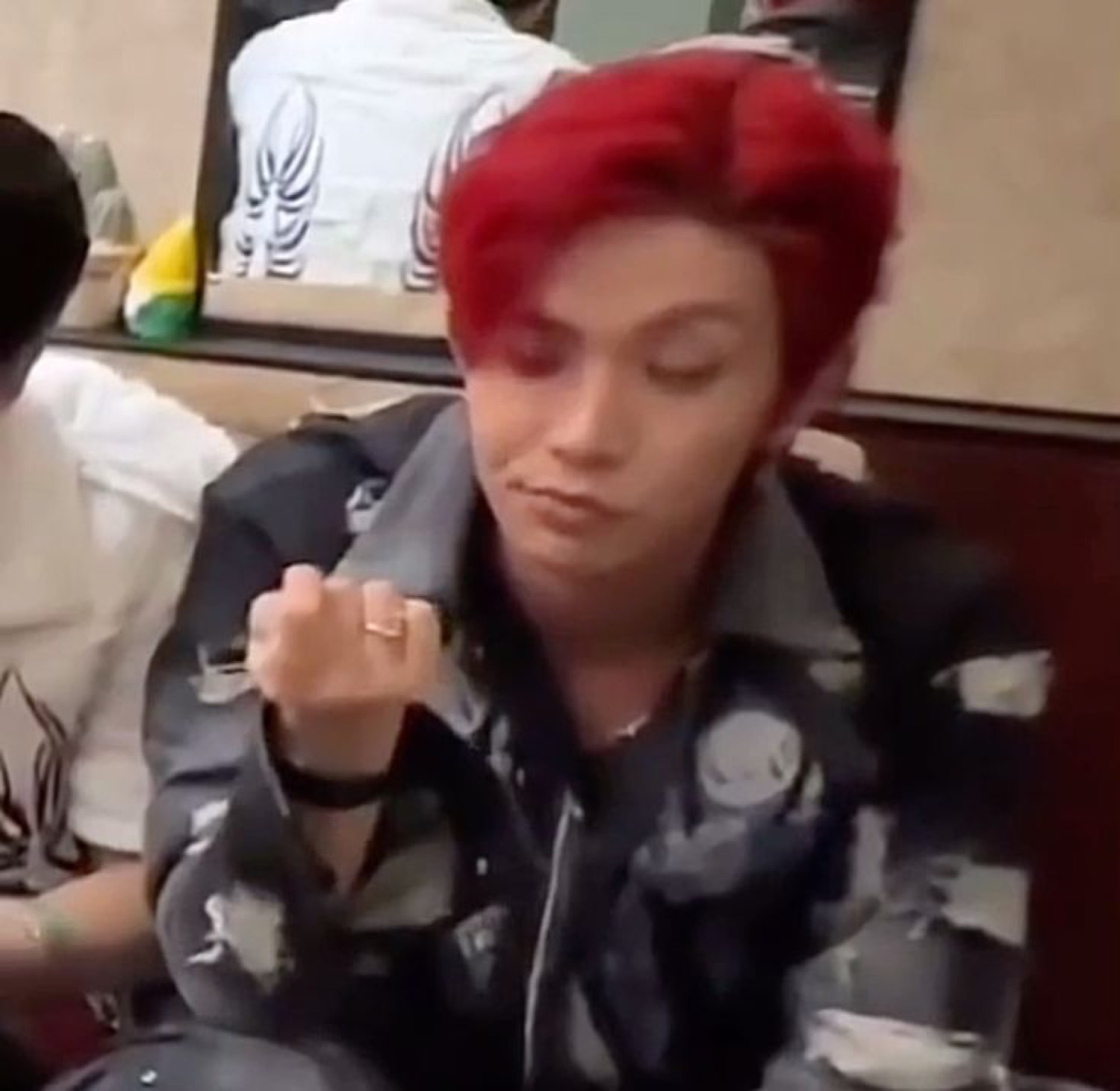 Red-haired person sitting with a flat, unbothered expression