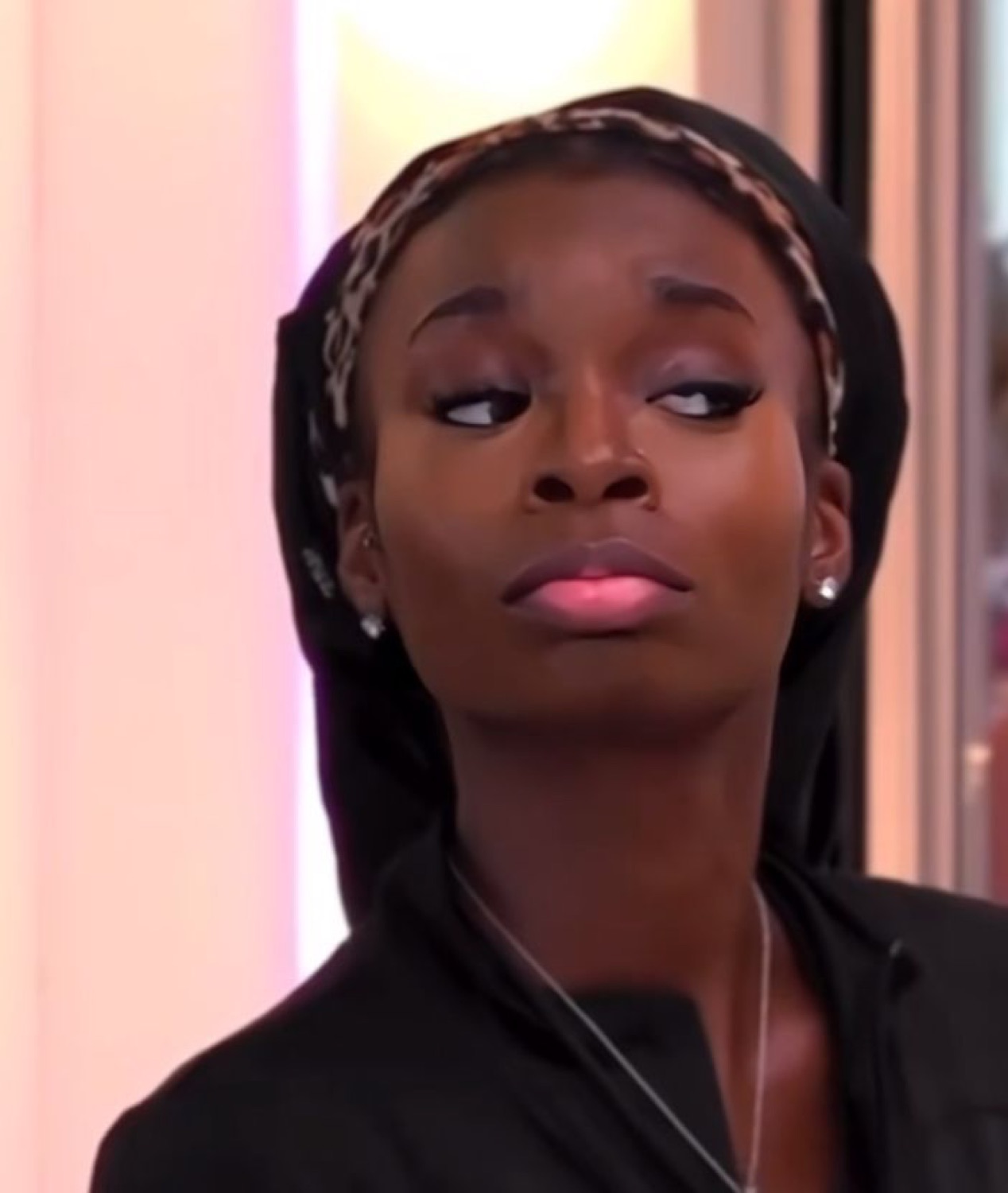 Woman in a hood cutting a skeptical side-eye with pursed lips