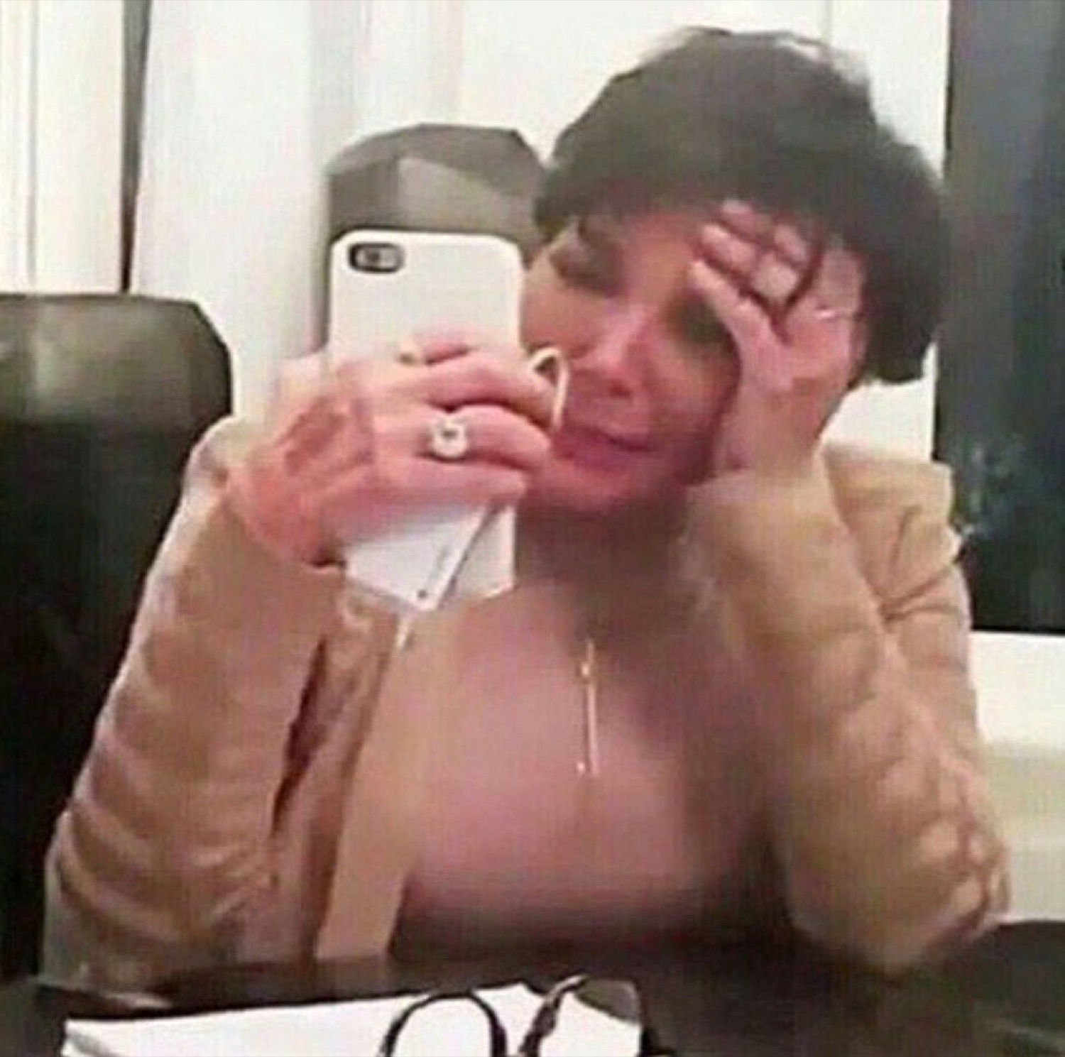 Kris Jenner crying with a hand on her forehead while on the phone