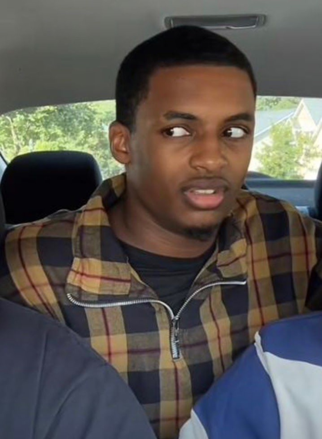 Man in a car giving a skeptical side-eye mid-sentence