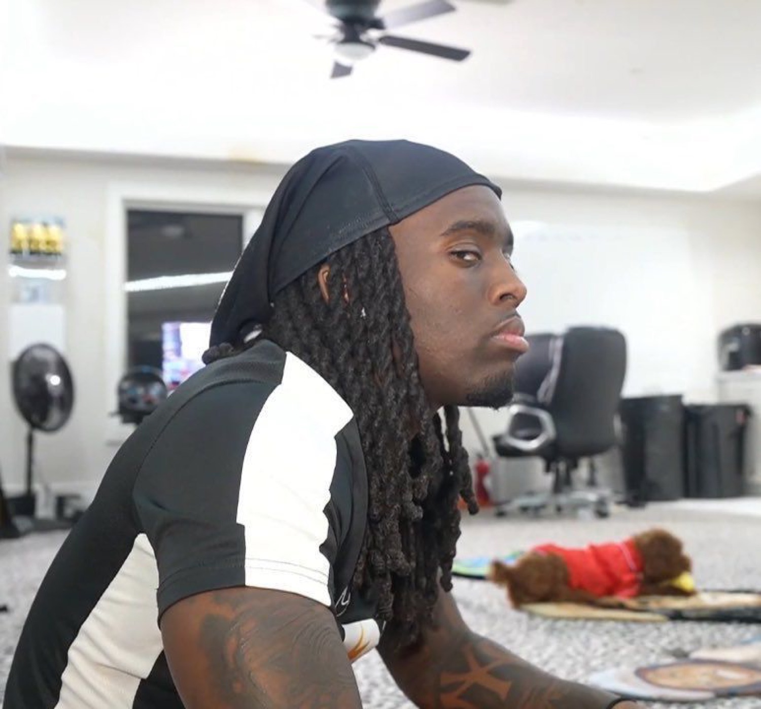 Man with locs leaning forward with a flat, unimpressed stare straight ahead