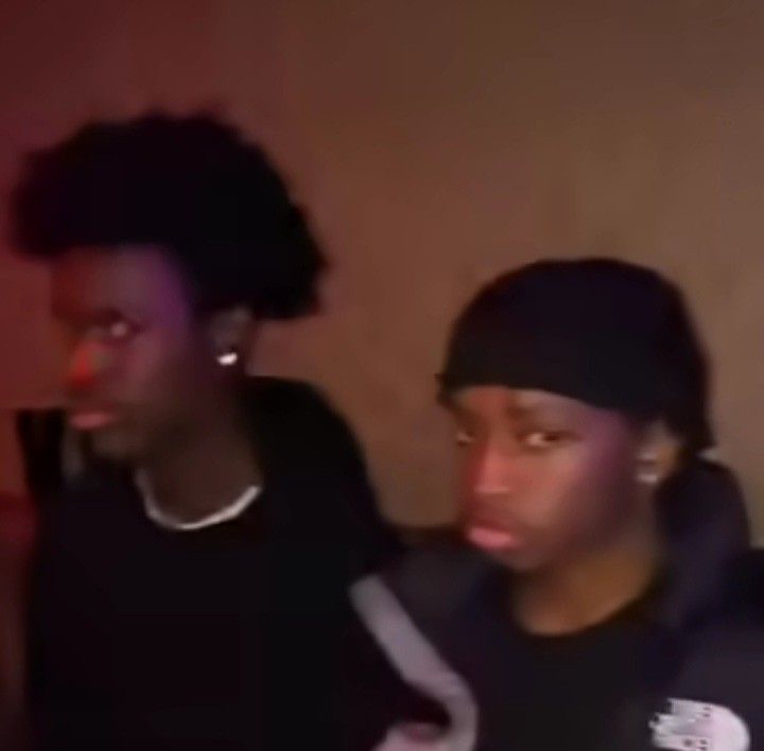 Two young guys in dim red lighting looking completely unimpressed and over it