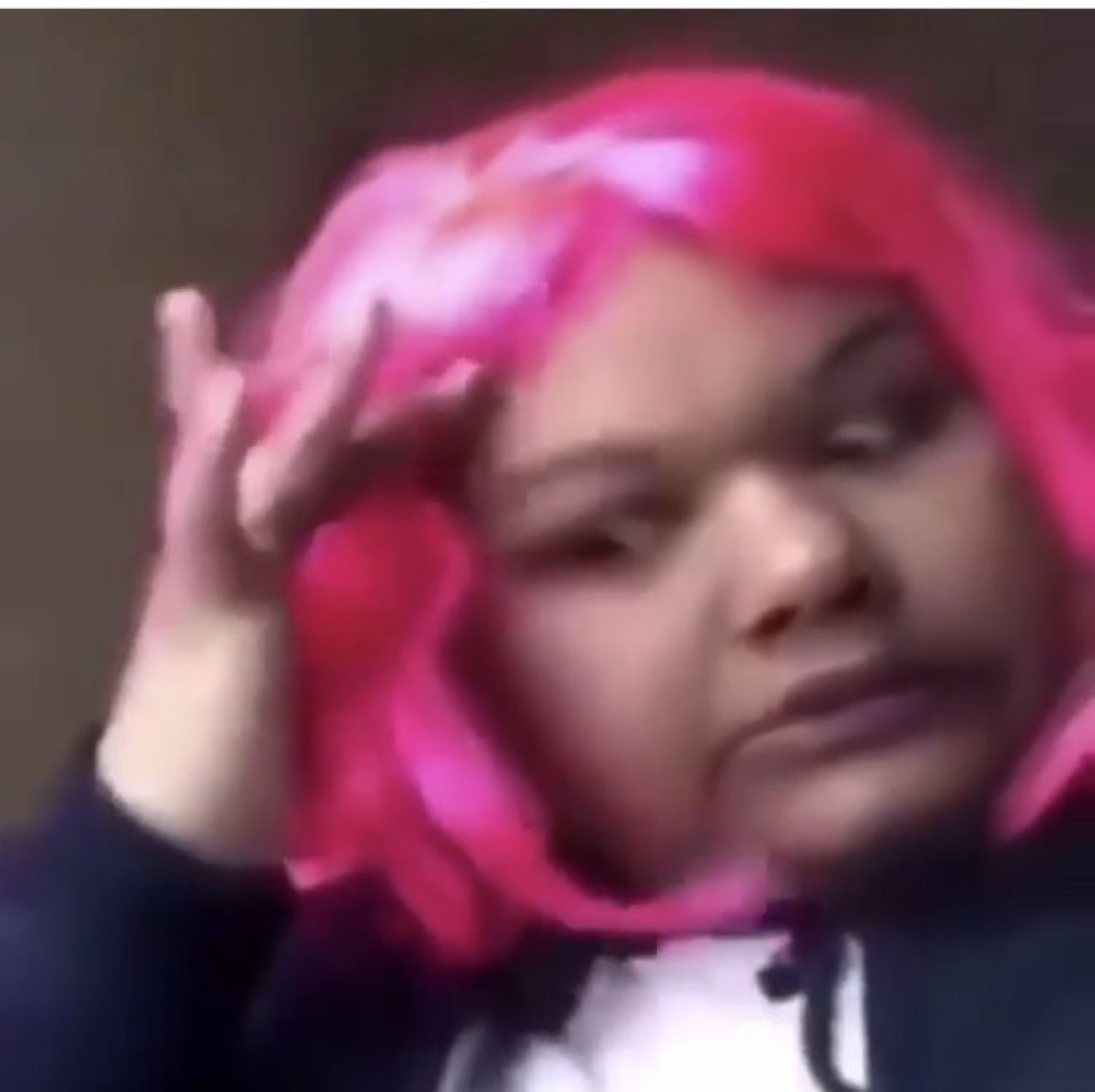 Person in a pink wig fixing their hair with a flat, unimpressed done-with-it look