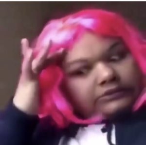Person in a pink wig fixing their hair with a flat, unimpressed done-with-it look