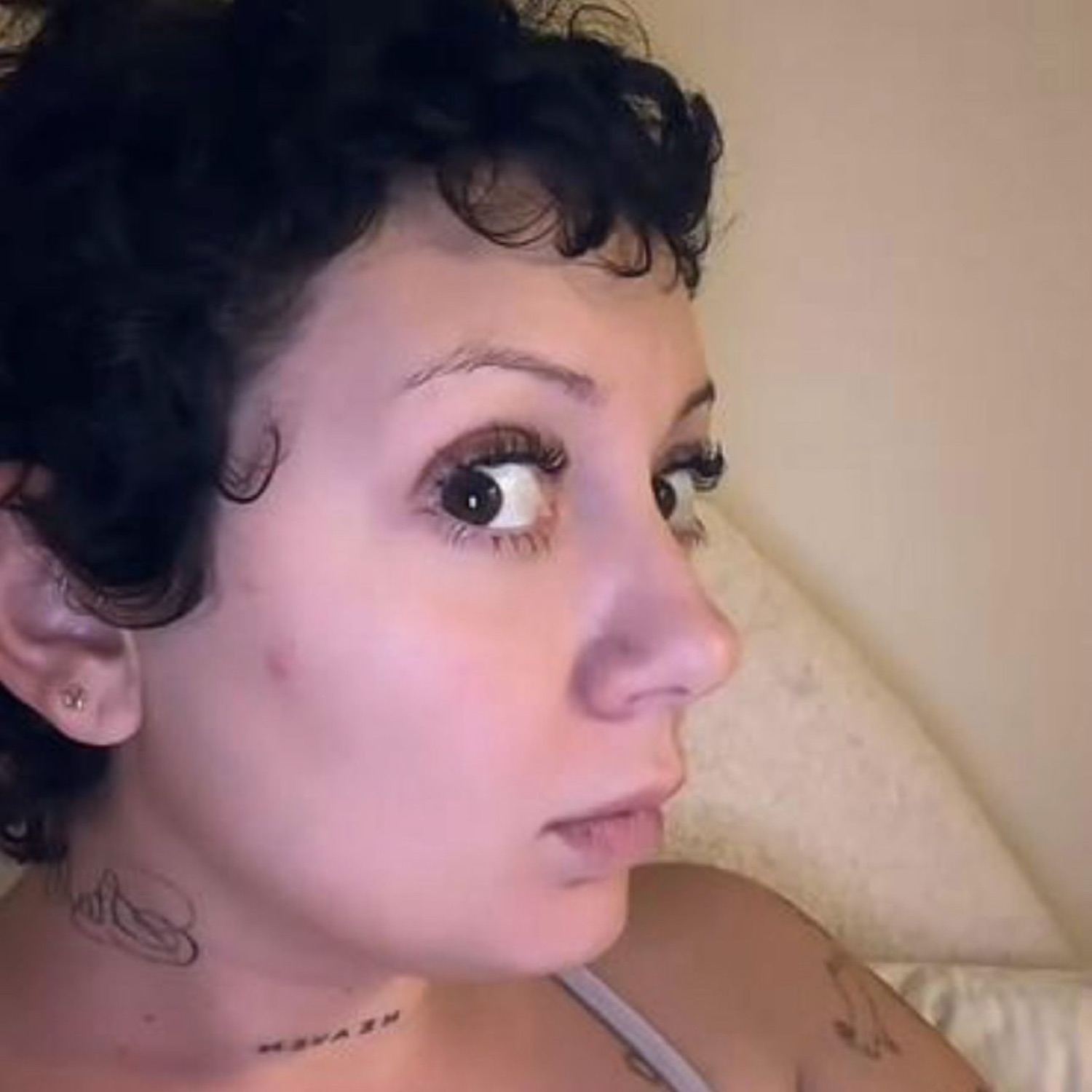 Woman with curly hair cutting a wide-eyed, sidelong stare off to the side