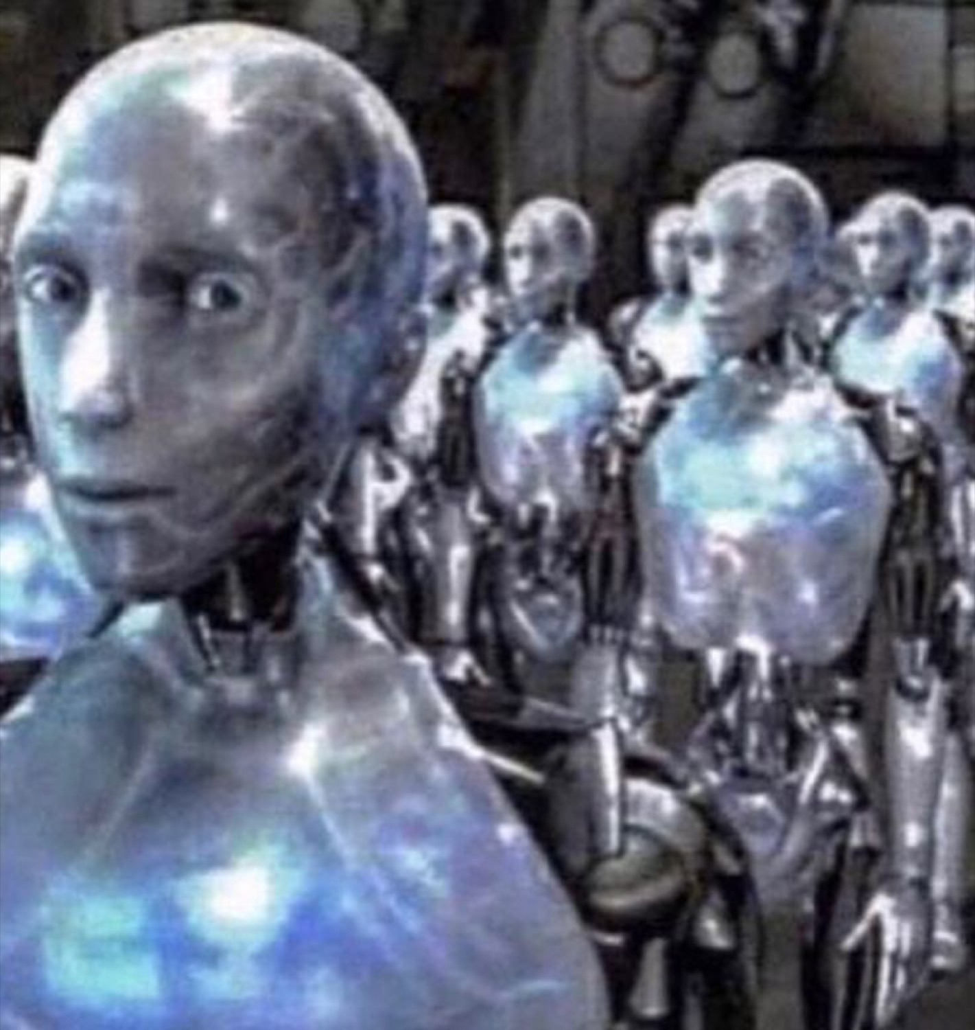 Silver movie robot turning to the camera with a wide, startled stare among a crowd of robots