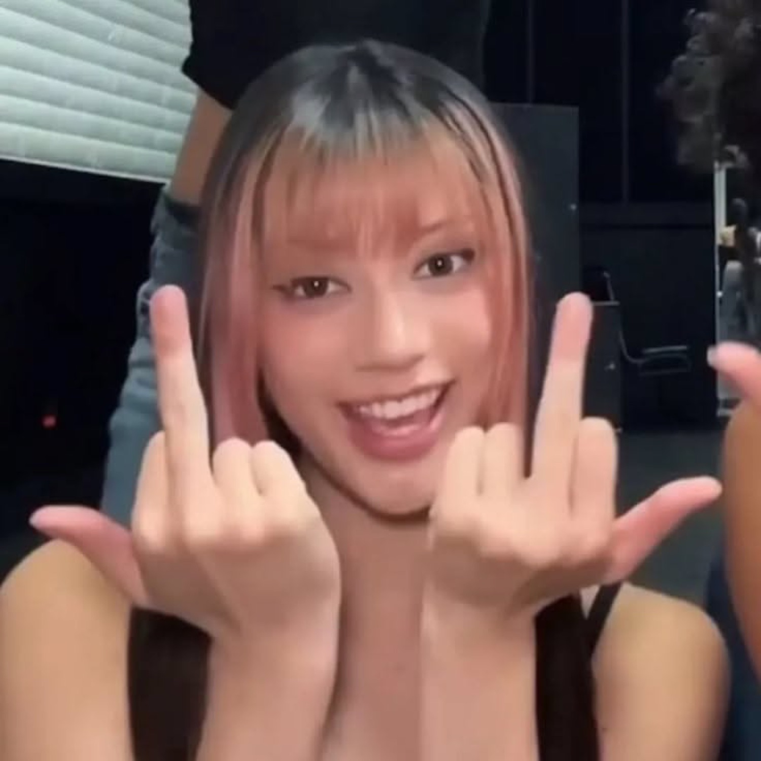 Girl grinning and throwing up double middle fingers at the camera