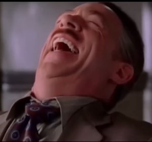 Man in a suit throwing his head back in a full, uncontrollable laugh