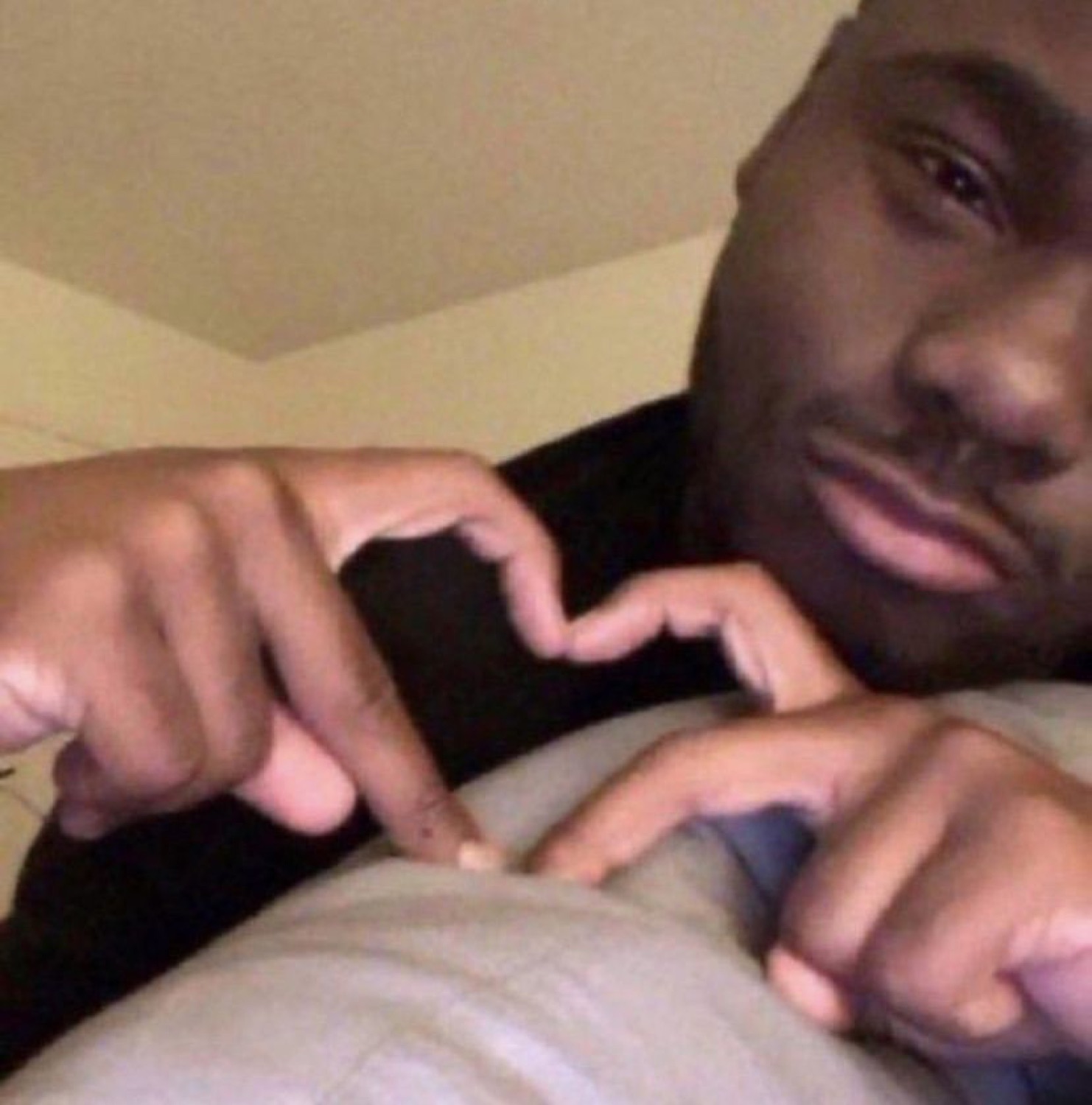 Man lying down with a sly smirk, fingers steepled together in a plotting gesture