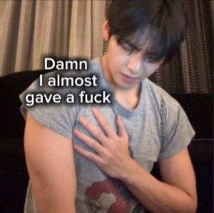 Young man clutching his chest with a smug unbothered face captioned 'Damn I almost gave a fuck'