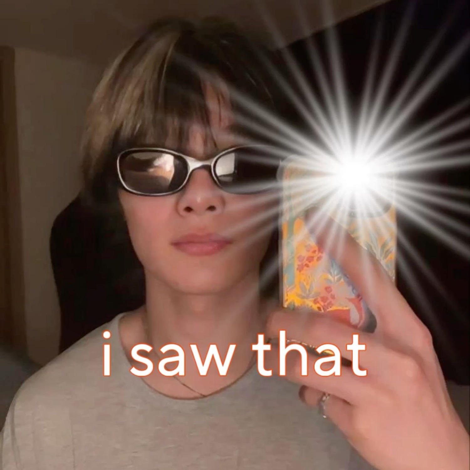Person in sunglasses holding a flashing phone captioned 'i saw that'