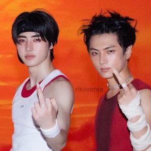 Two K-pop-style young men staring coldly at the camera while both give the middle finger