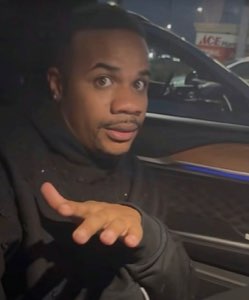 Guy in a car at night turning around with an open palm, like 'what was that'