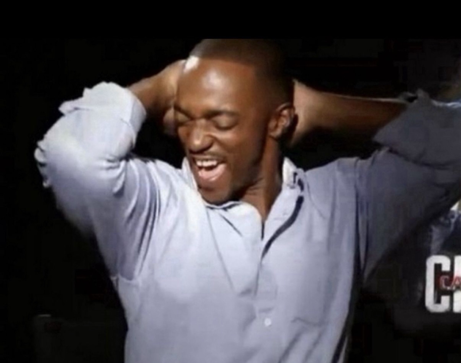 Man clutching his head and laughing with relief in a dim room