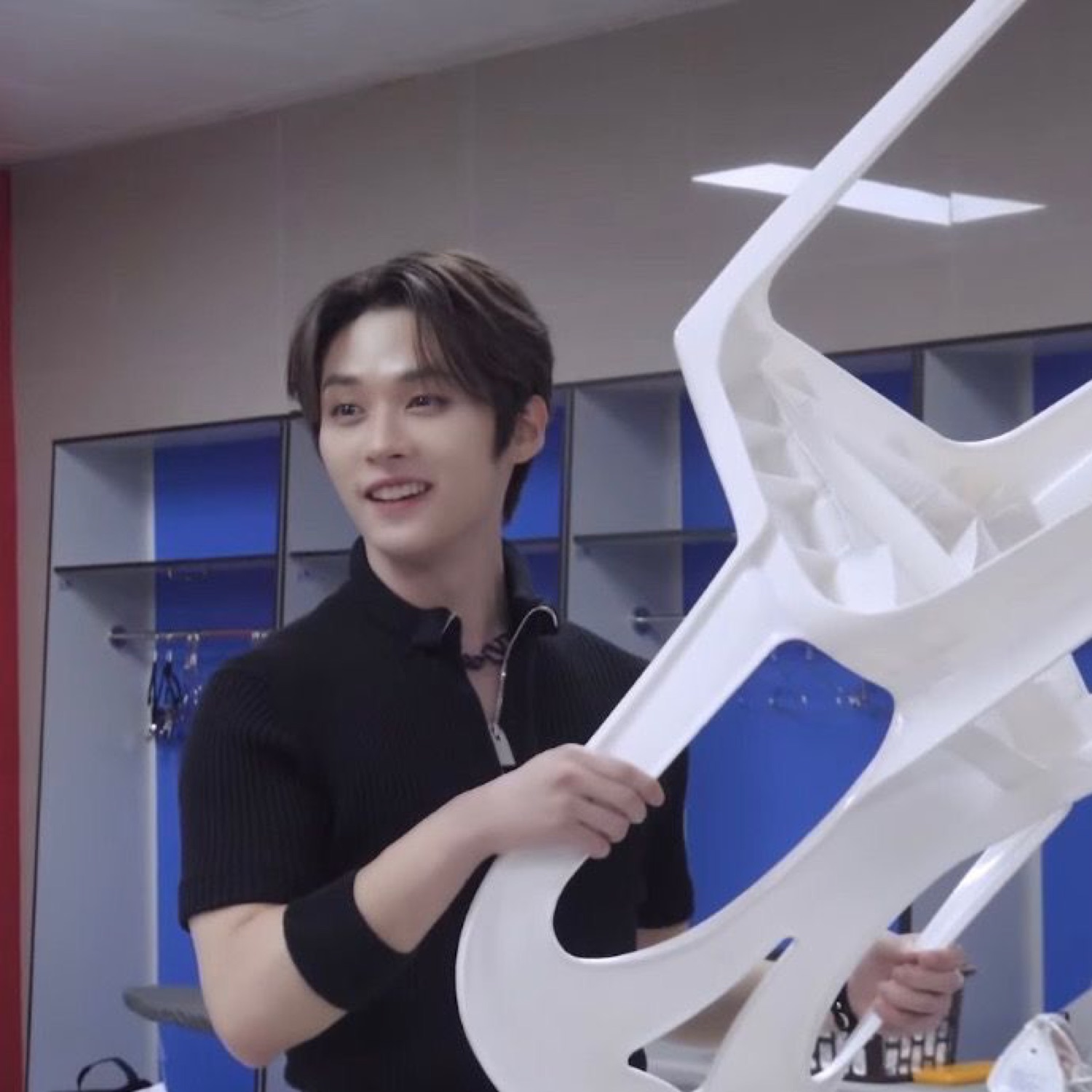 Smiling guy hoisting a big white chair up in a locker room