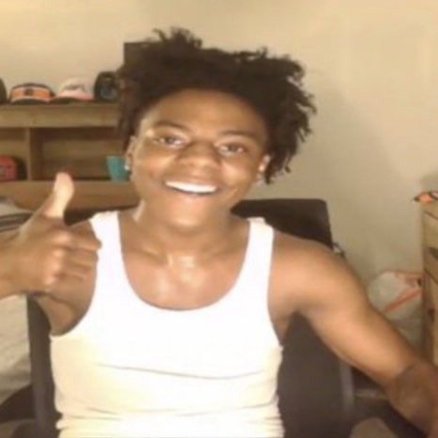 Grinning guy in a white tank top throwing an enthusiastic thumbs up