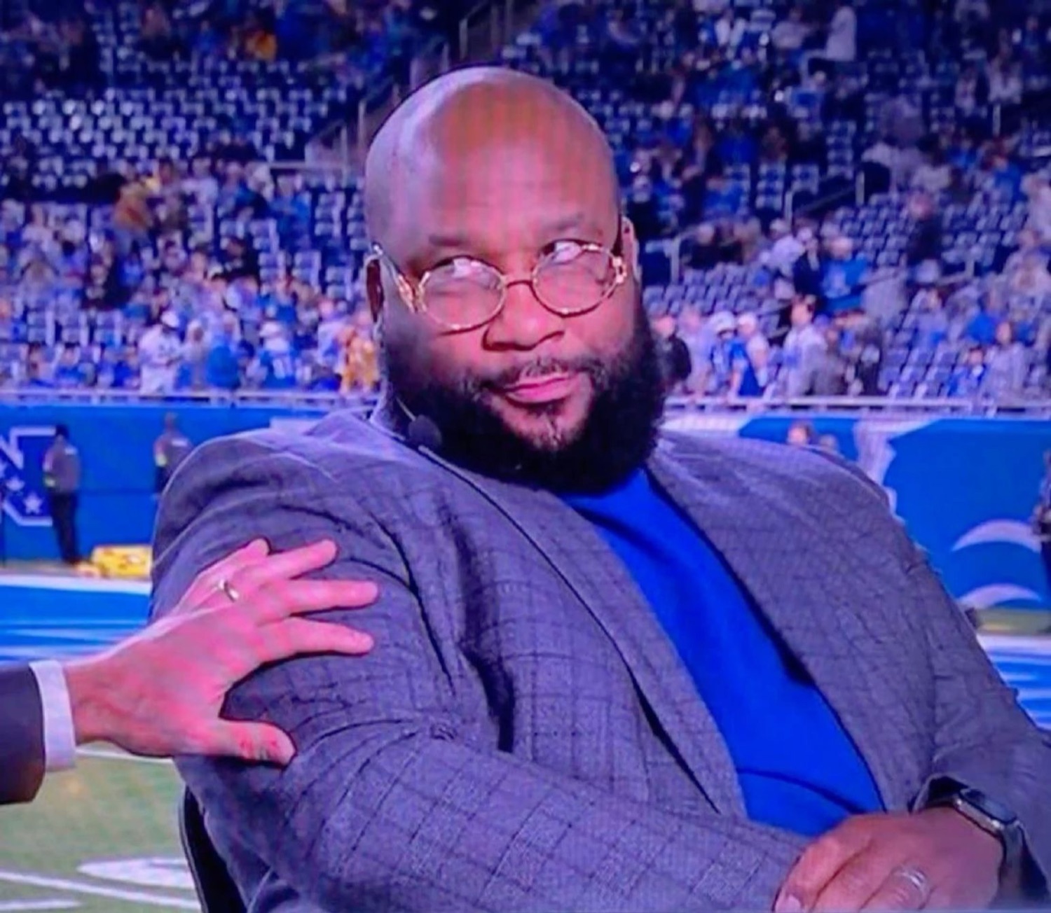 Bearded analyst in a stadium cutting a slow side-eye at whoever grabbed his shoulder