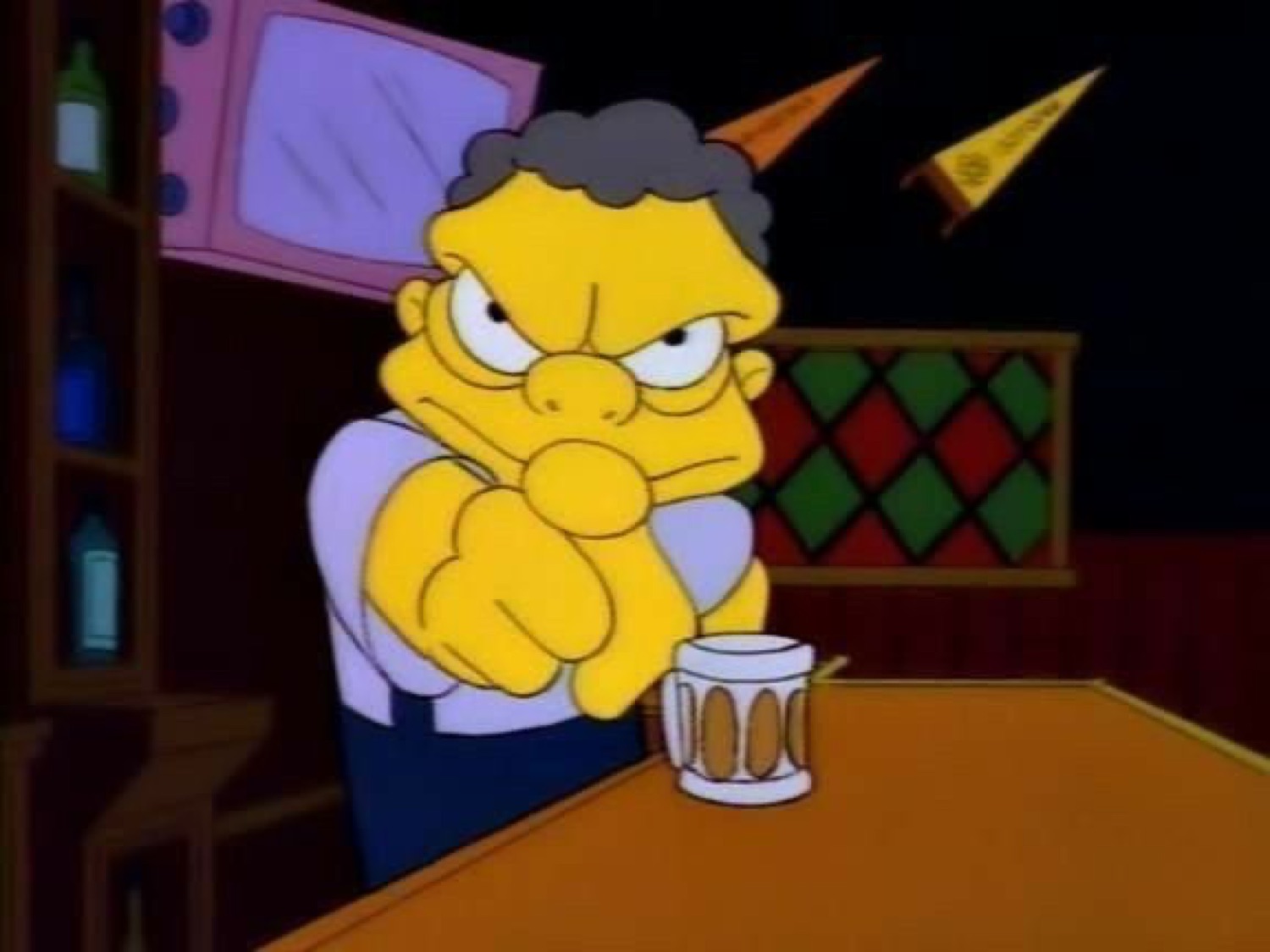 Moe from The Simpsons scowling intensely at a bar with a beer mug, arms crossed