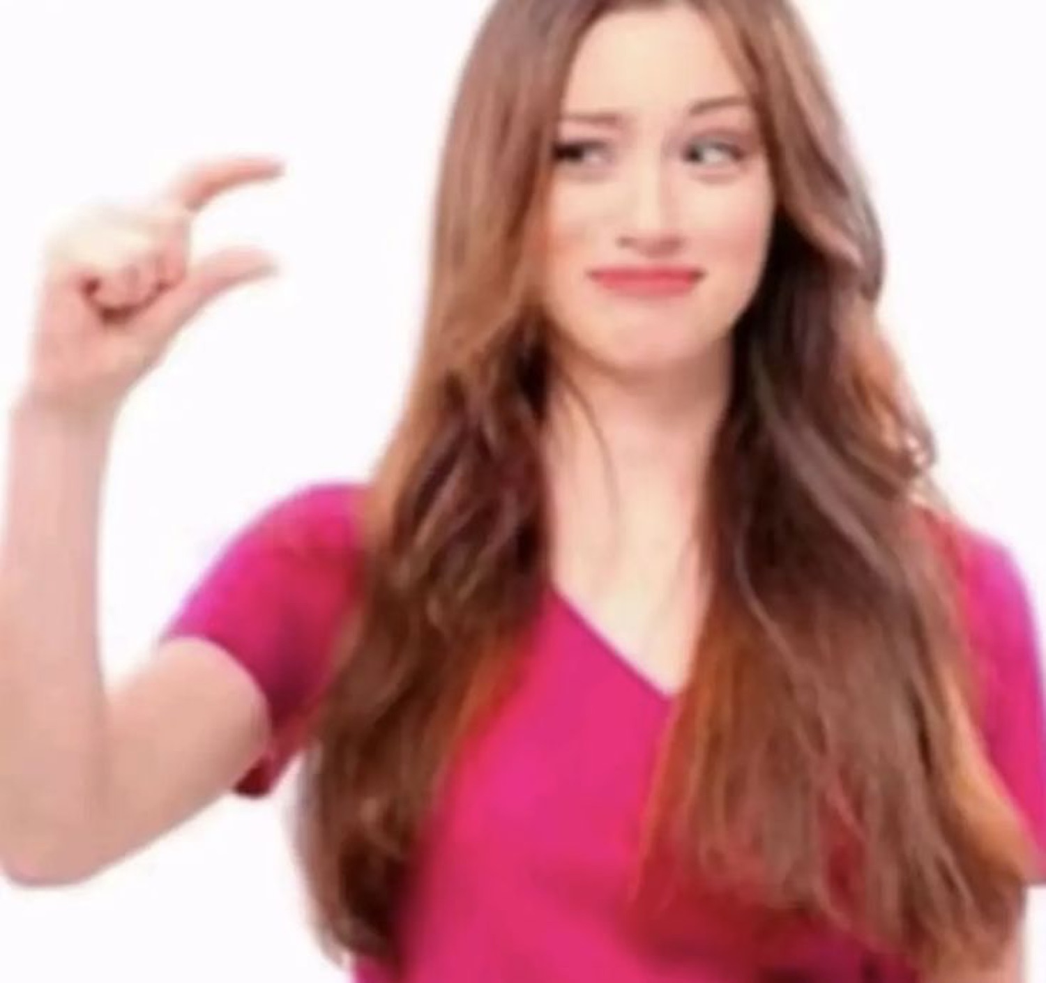 Woman in a pink top pinching her fingers to show a tiny amount with an awkward smile